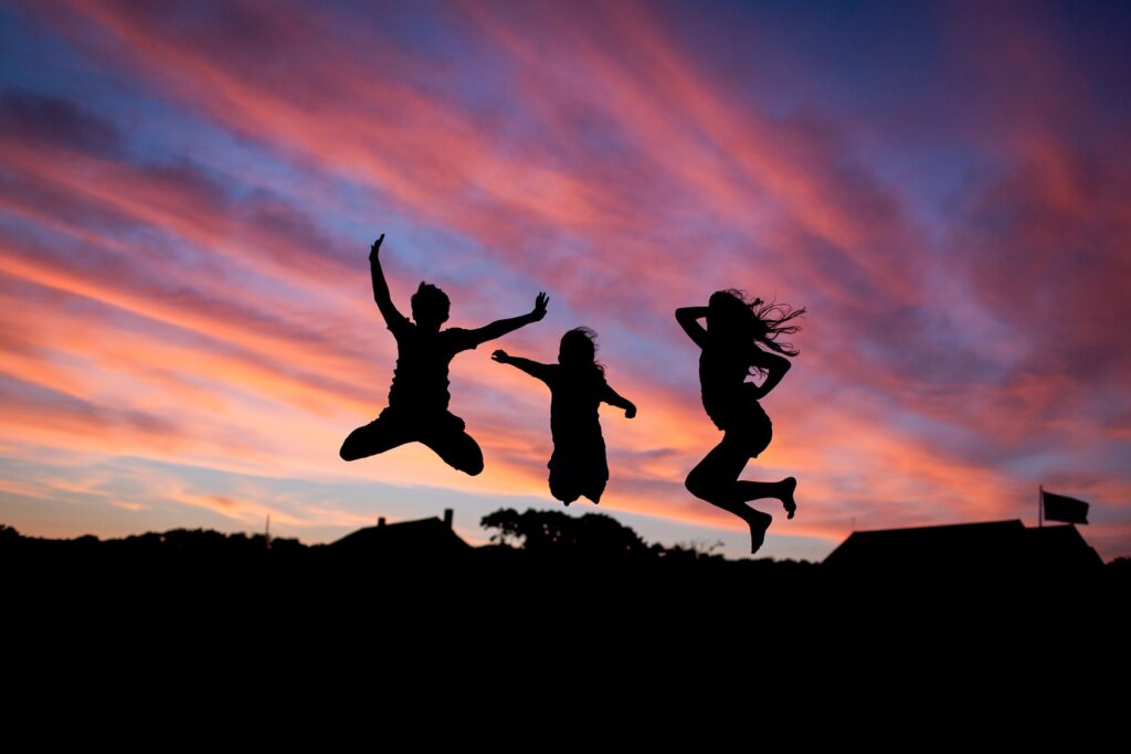 счастливые люди прыгают вверх к солнечным лучам